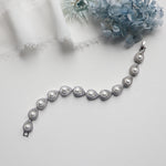 a silver bracelet with pearls on a white surface