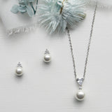 a necklace, earrings and a flower on a white surface