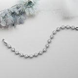 a silver bracelet on a white background with flowers