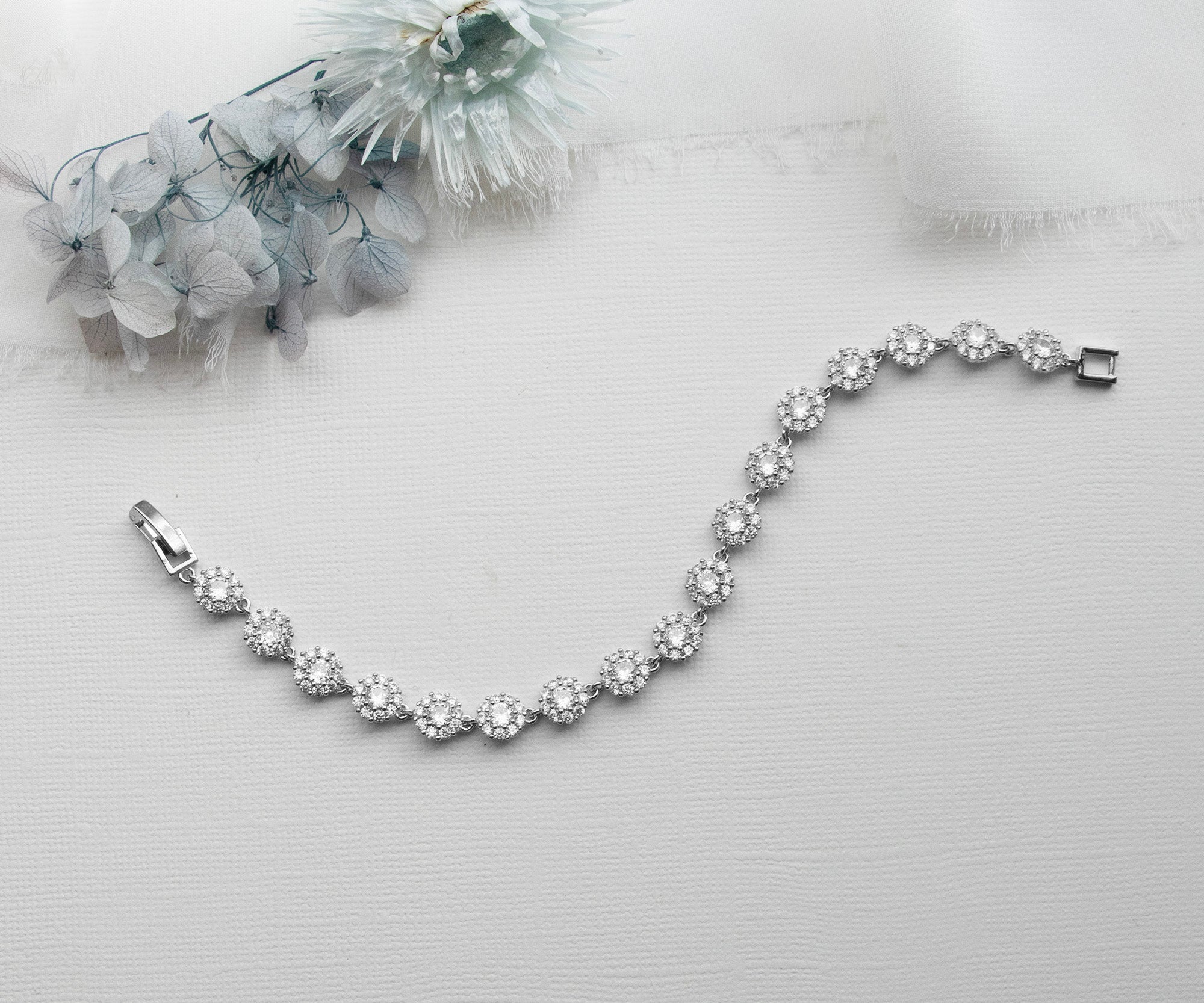 a silver bracelet on a white background with flowers
