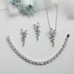 a necklace, earrings, and flower on a white surface