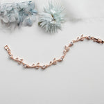 a rose gold chain bracelet on a white background