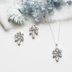 a necklace, earrings and a flower on a white surface