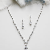 a necklace and earring set on a white surface