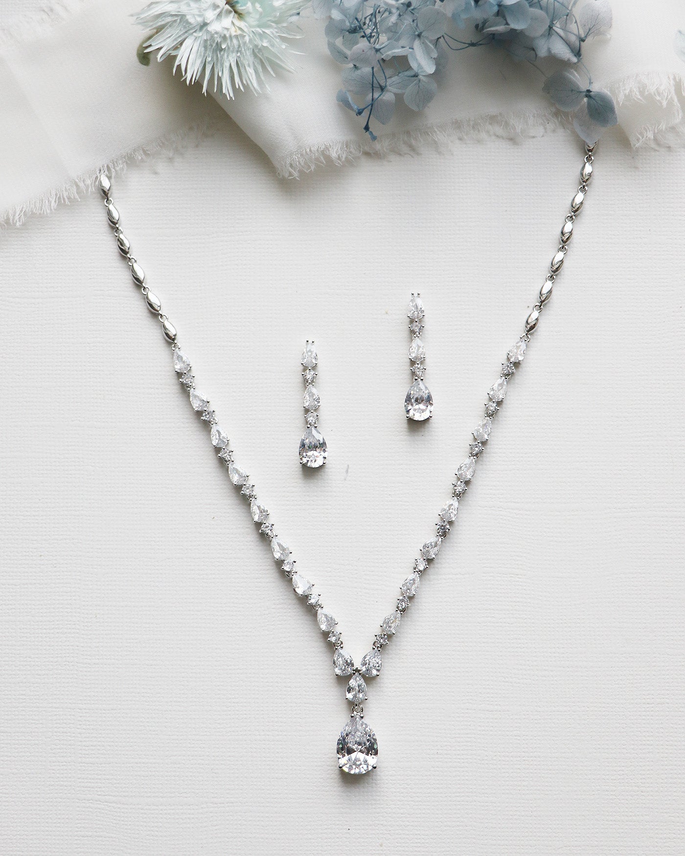 a necklace and earring set on a white surface