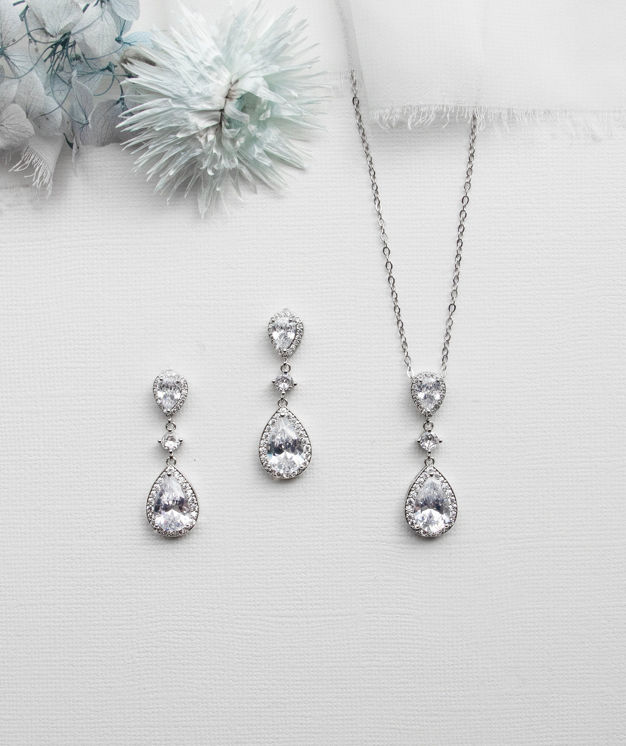 a necklace, earrings and a flower on a white background