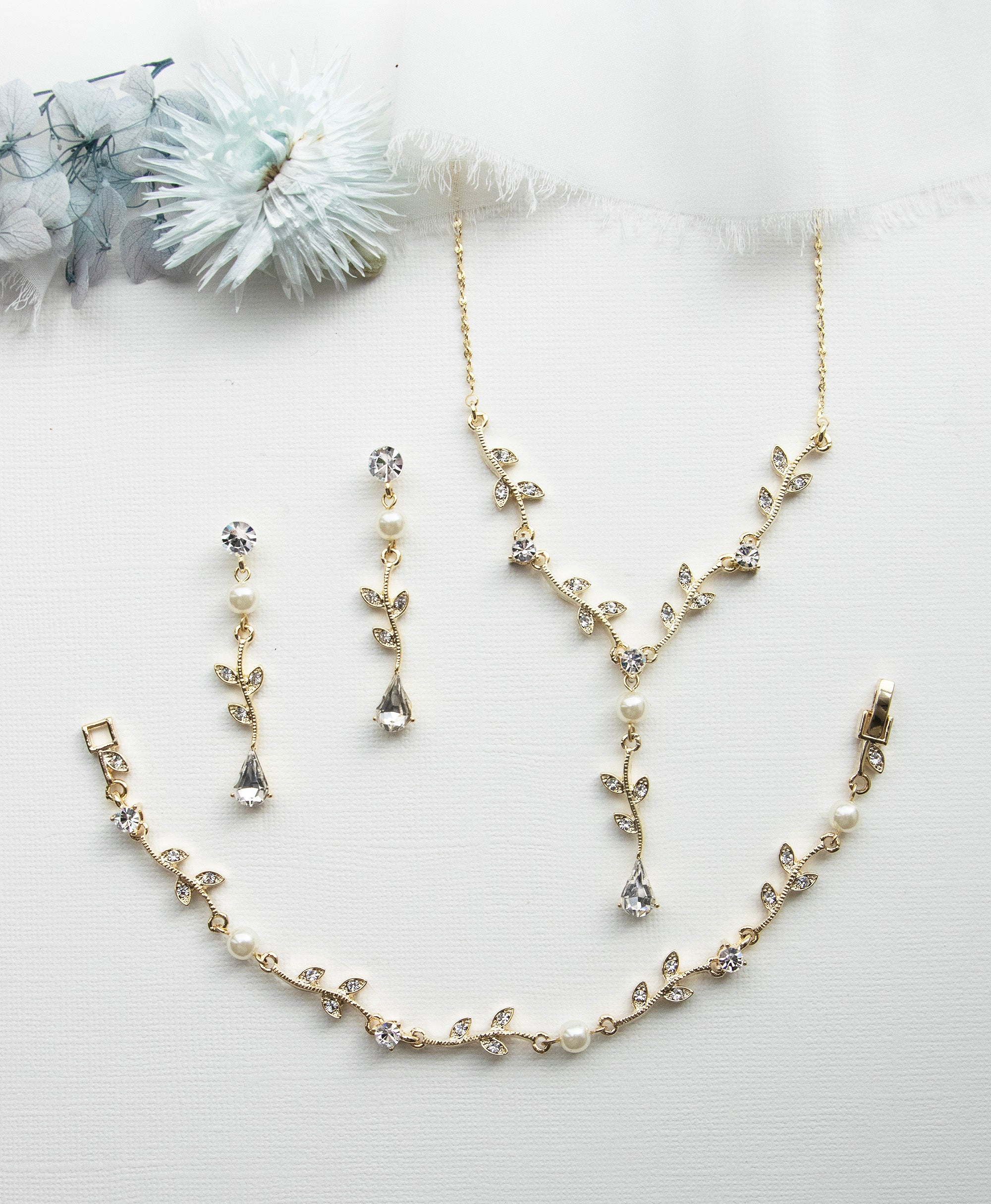 a necklace, bracelet, and earring set on a white surface
