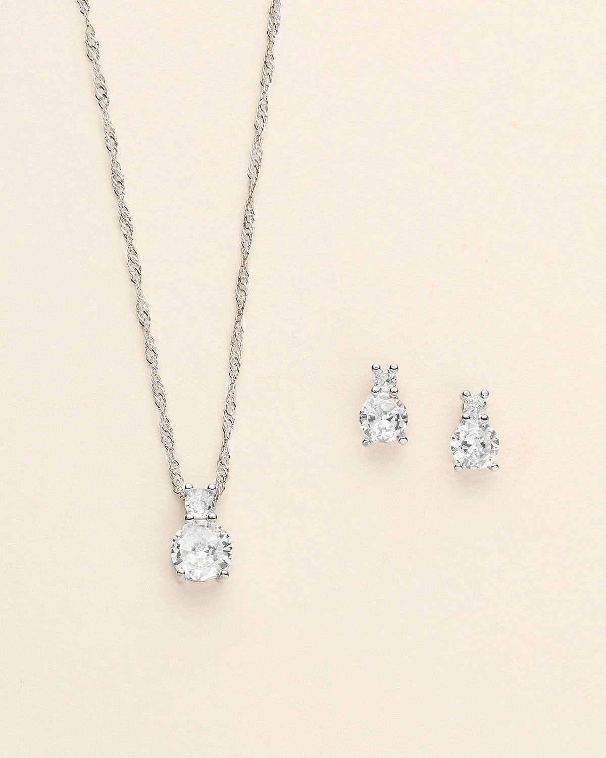 a pair of earrings and a necklace on a white background