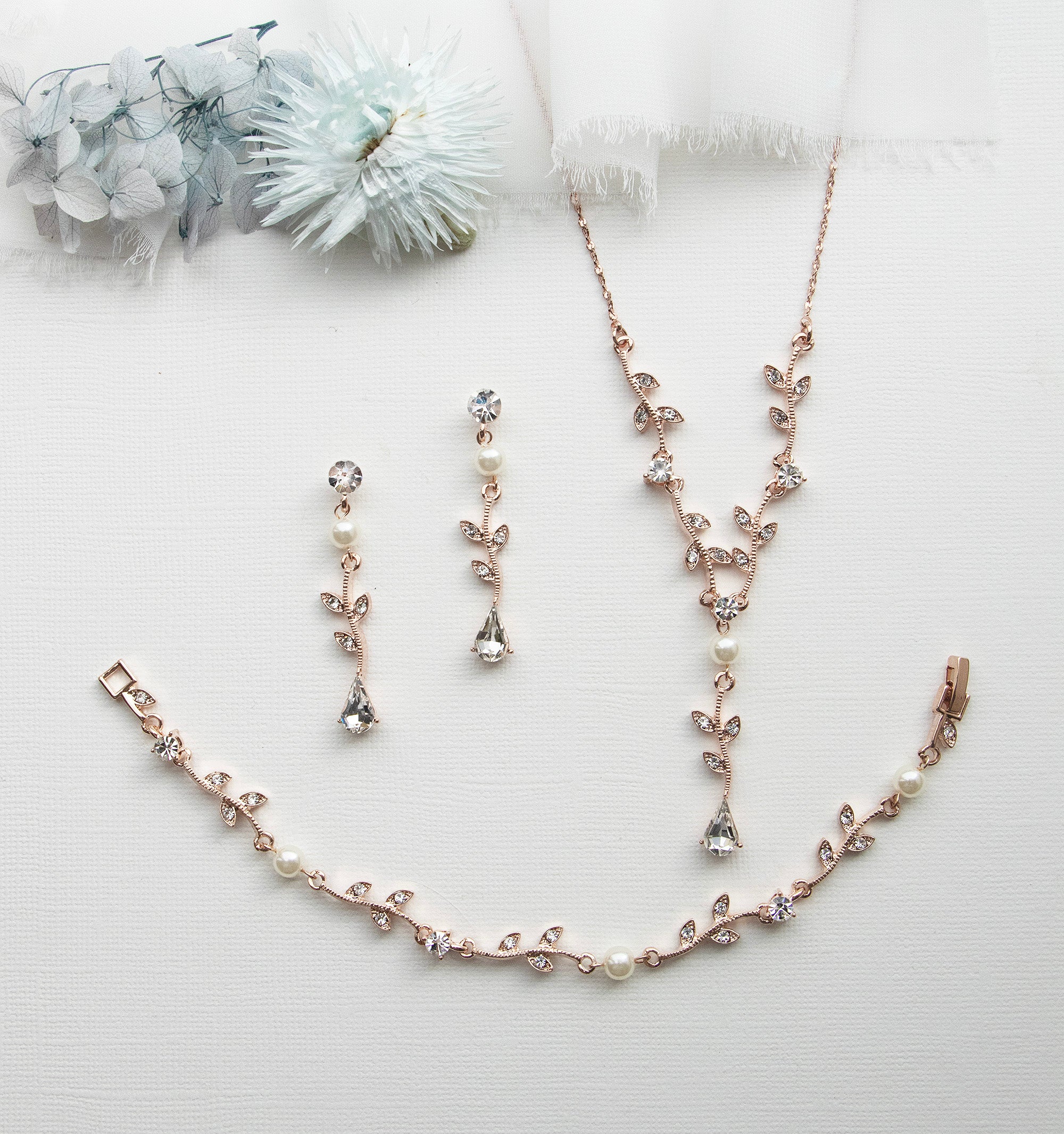 a necklace, bracelet, and earring set on a white surface