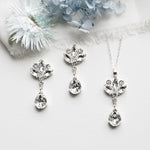 a necklace, earrings, and flower on a white surface