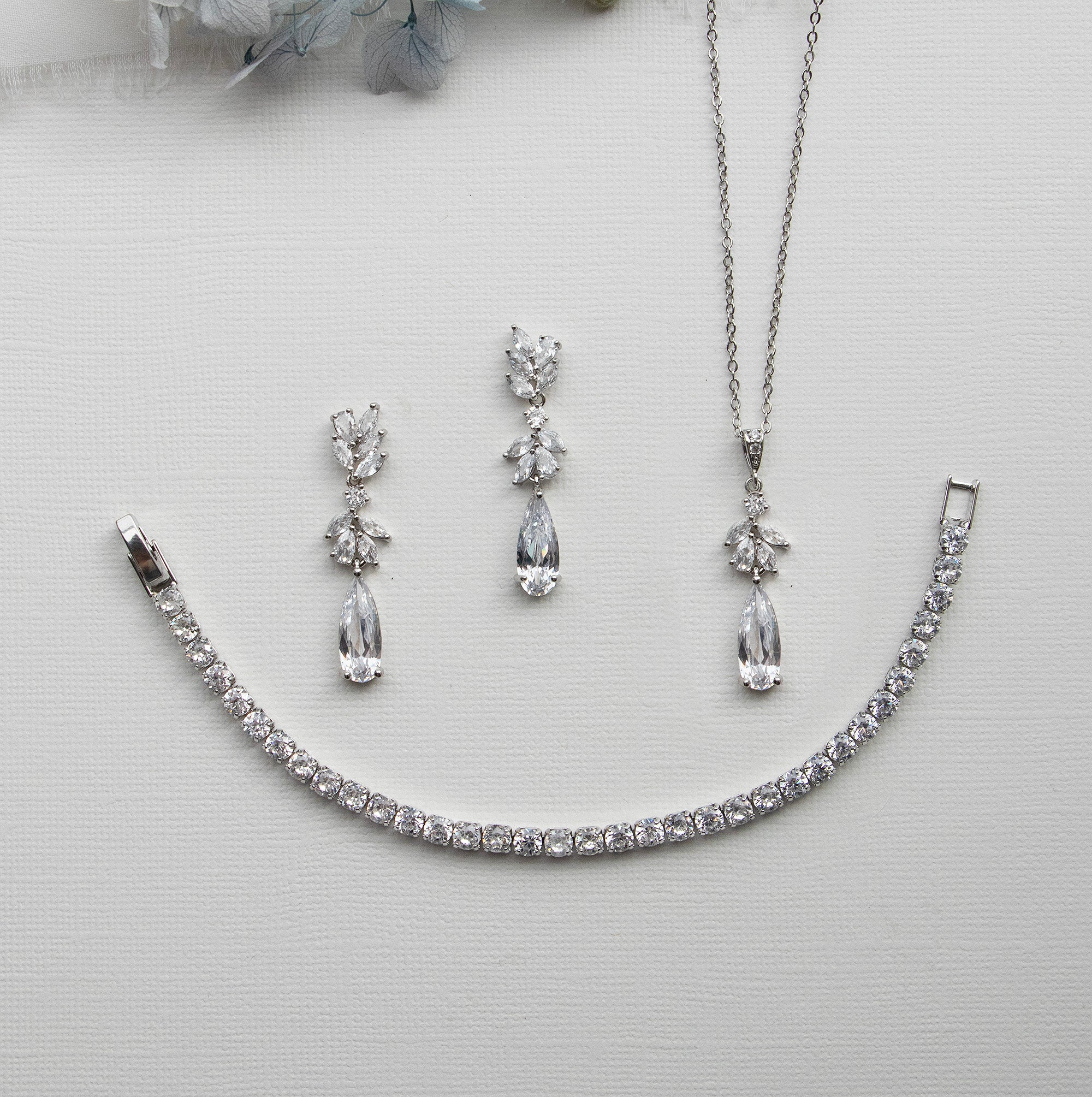 a necklace, bracelet, and earring set on a white surface