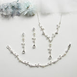 a necklace, bracelet, and earring set on a white surface