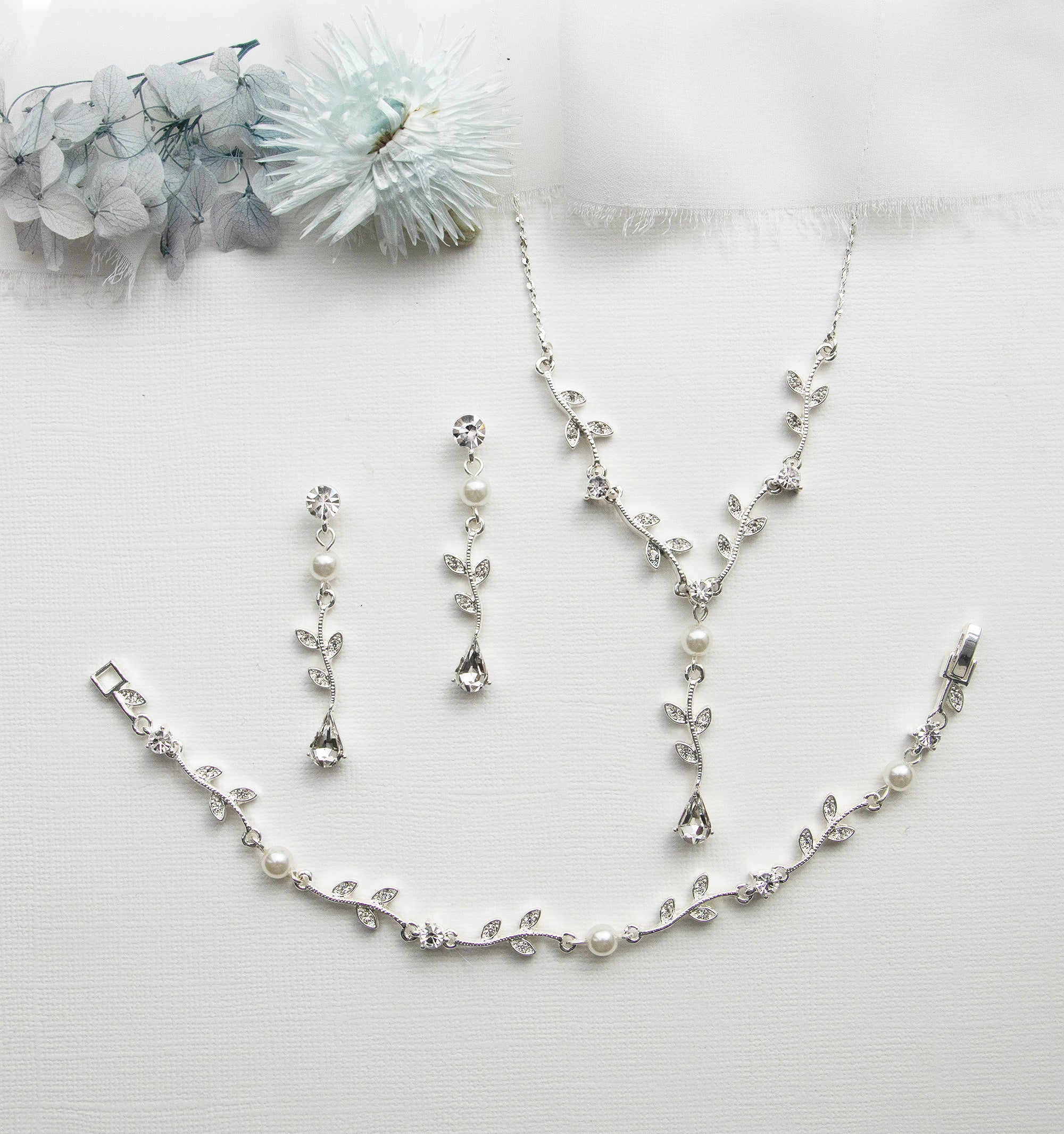 a necklace, bracelet, and earring set on a white surface