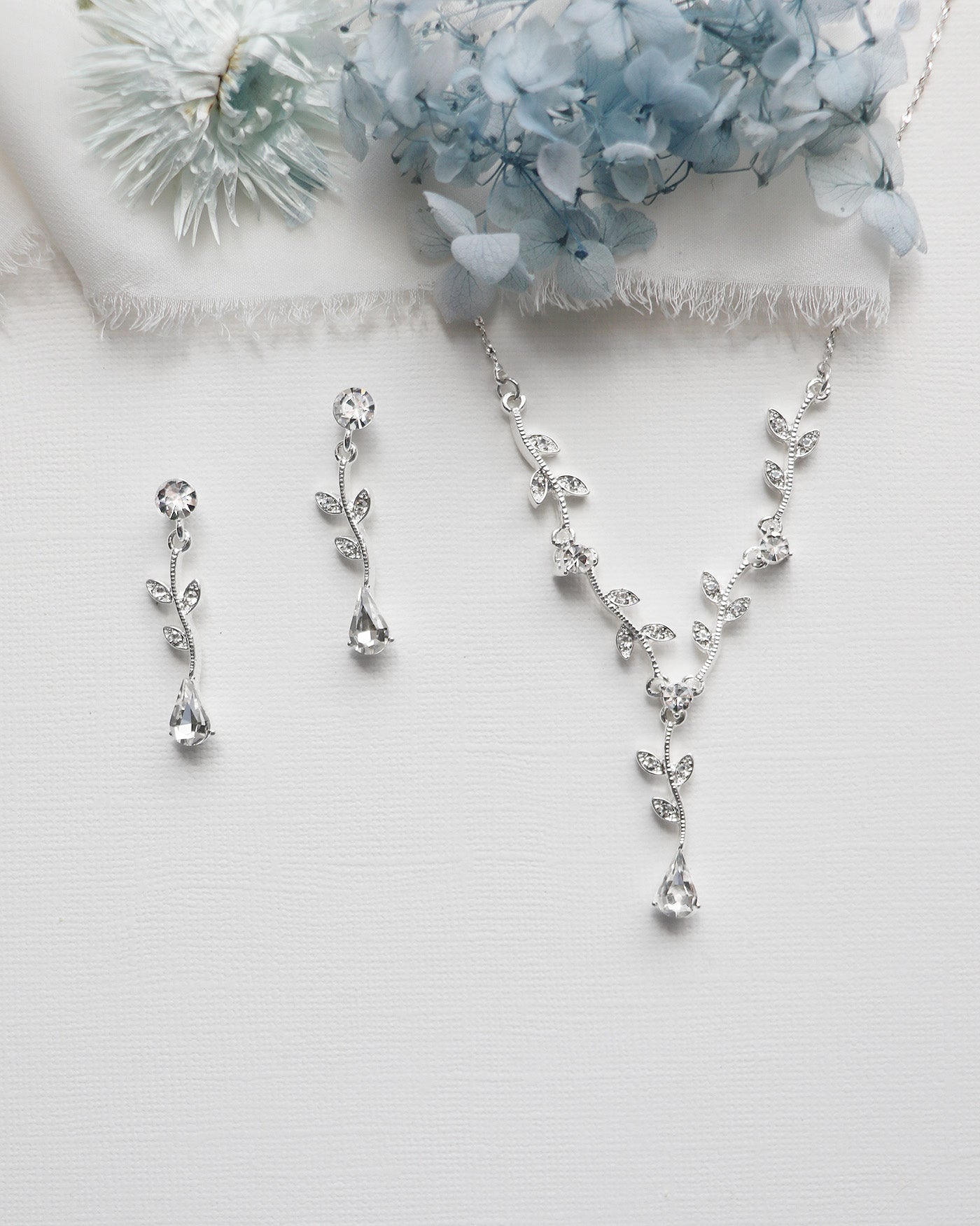 a necklace, earrings, and a bouquet of flowers on a table