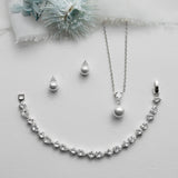 a necklace, earrings, and a flower on a white surface