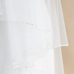A close-up view of a delicate white wedding veil with a delicate beaded design.