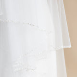 A close-up view of a delicate white wedding veil with a delicate beaded design.