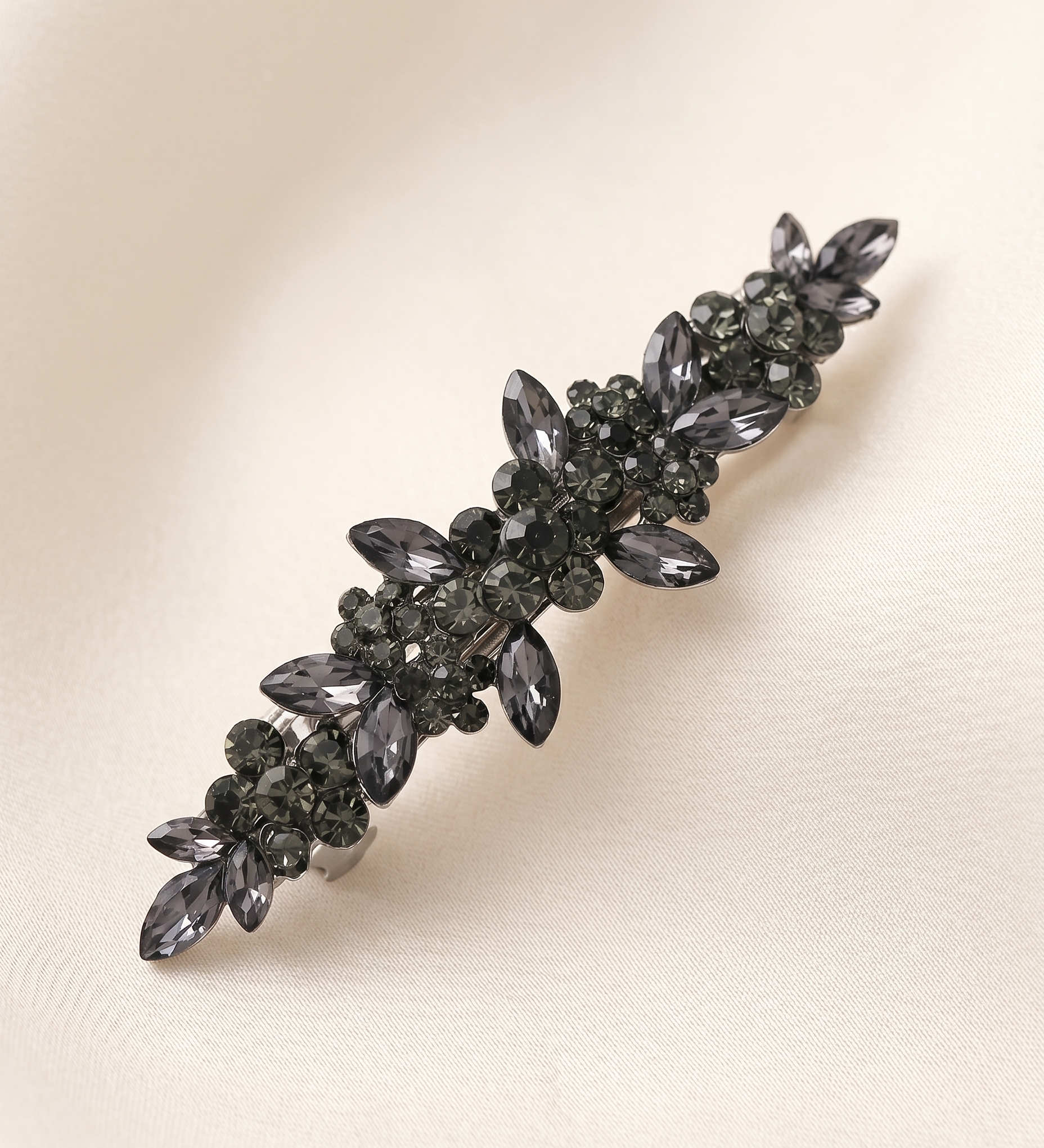 A decorative hair clip with a floral design and numerous small black gemstones.