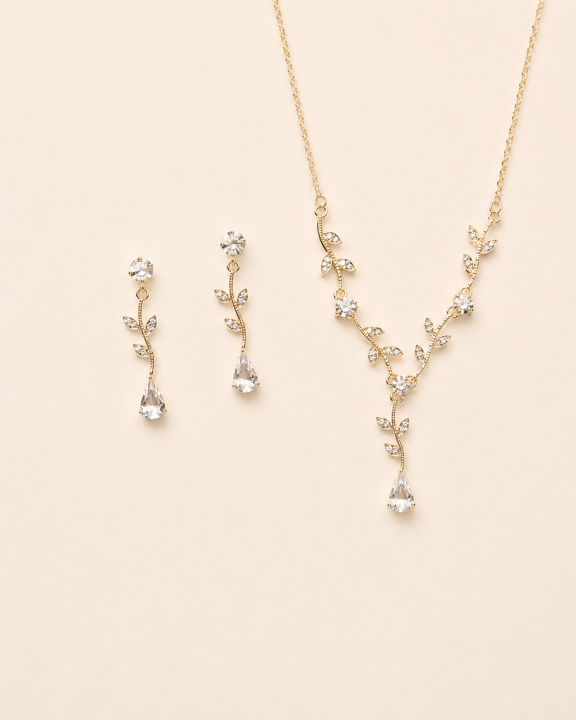 A delicate gold necklace and earrings set with small, clear gemstones.