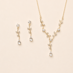 A delicate gold necklace and earrings set with small, clear gemstones.
