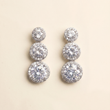 A pair of elegant diamond earrings with multiple tiers of round stones set in a halo-like design.