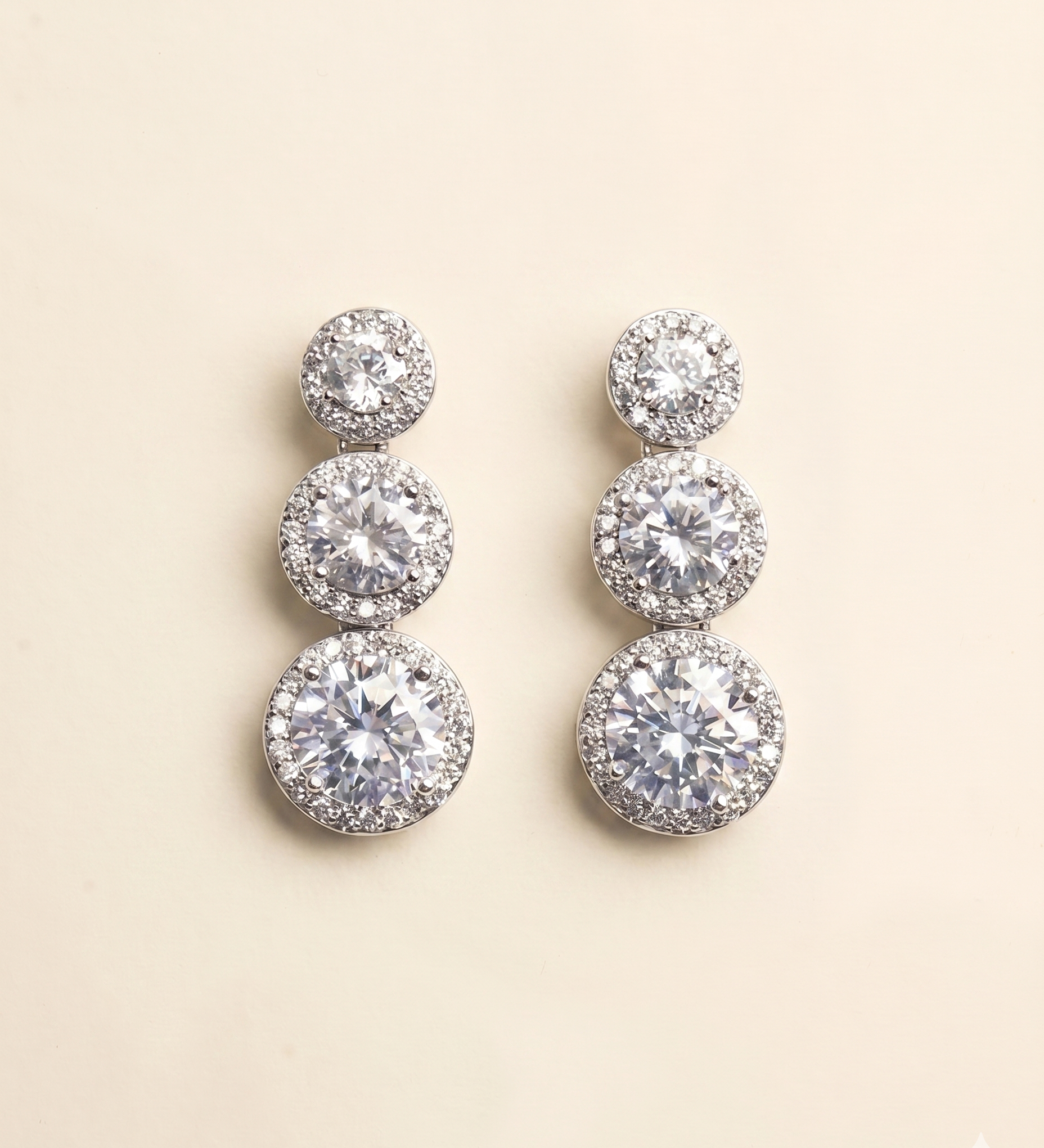 A pair of elegant diamond earrings with multiple tiers of round stones set in a halo-like design.