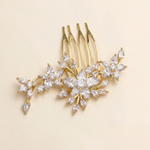 A gold-colored hair accessory with a floral design, featuring multiple small, clear gemstones or crystals arranged in a decorative pattern.