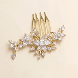 A gold-colored hair accessory with a floral design, featuring multiple small, clear gemstones or crystals arranged in a decorative pattern.