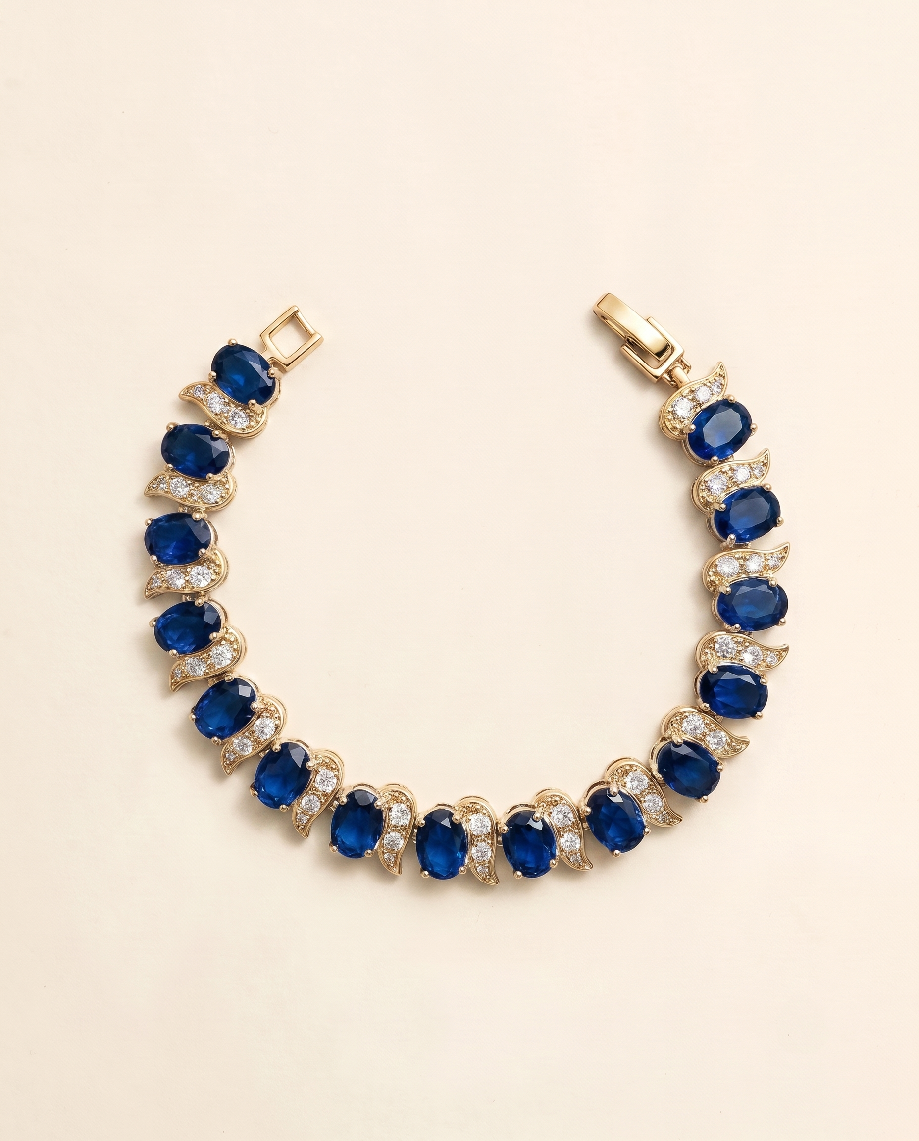 A gold bracelet adorned with blue and white gemstones, including diamonds, is displayed against a light background.