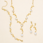 a set of gold jewelry pieces, including a necklace, earrings, and a bracelet, all adorned with small, clear gemstones.