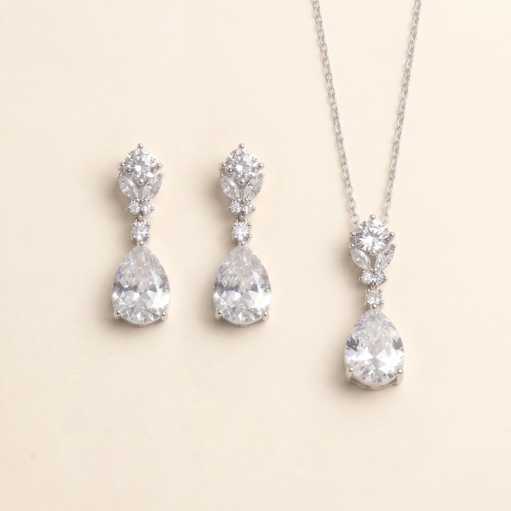 A necklace and earrings set made of white diamonds, arranged on a light beige background.