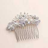 A silver hairbrush adorned with a decorative floral design and sparkling crystal elements.