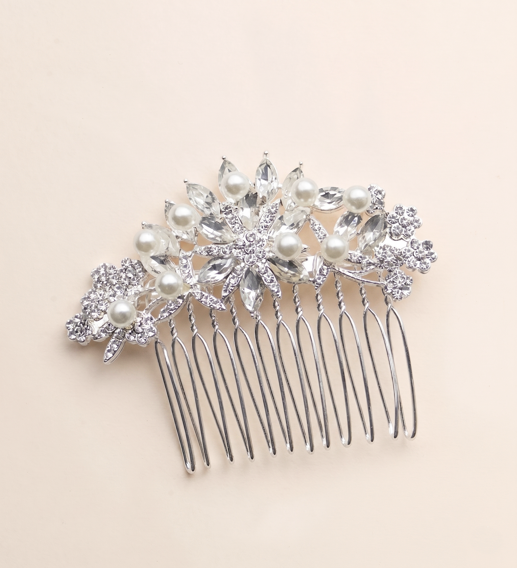 A silver hairbrush adorned with a decorative floral design and sparkling crystal elements.