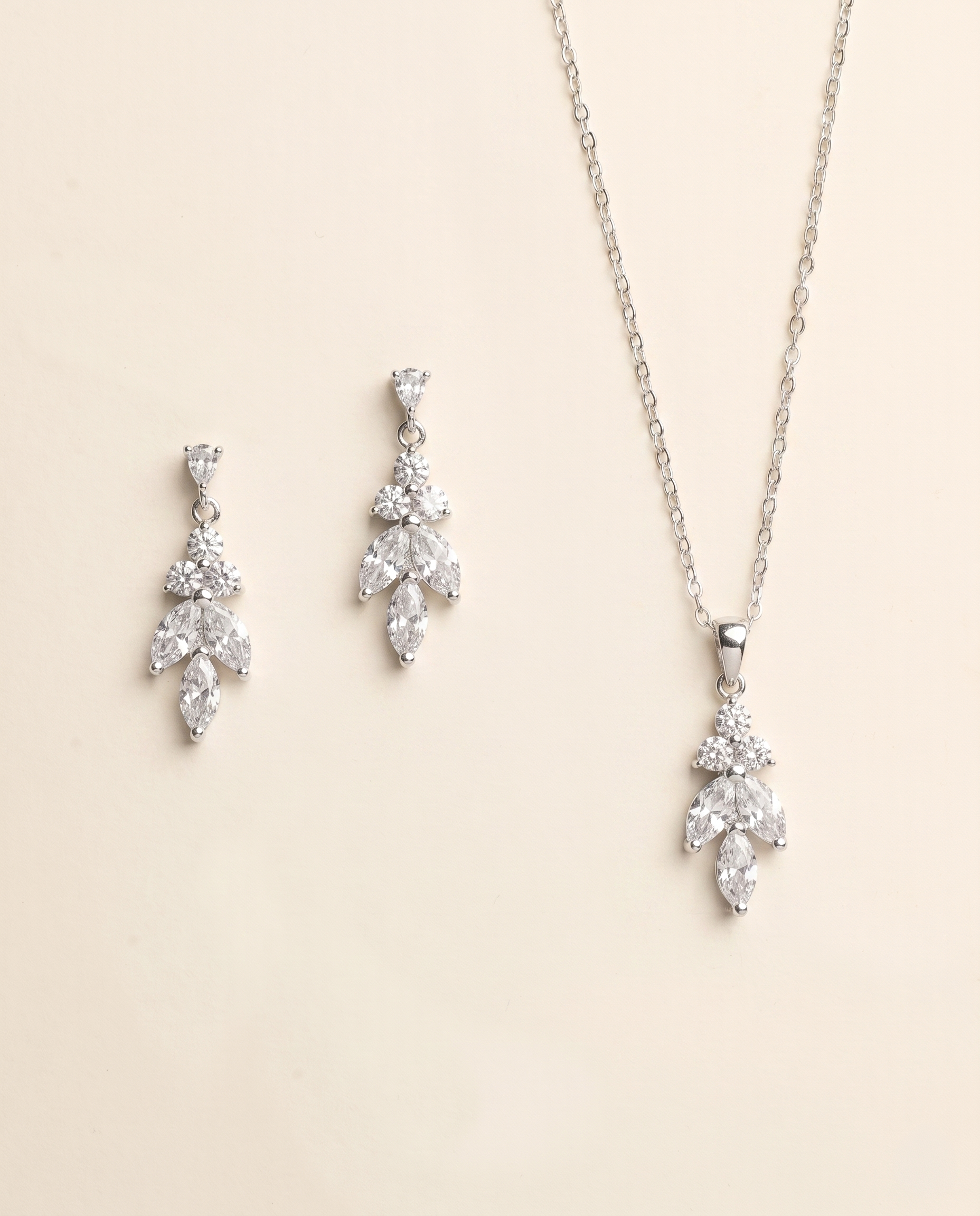 a necklace and earrings set against a light beige background.