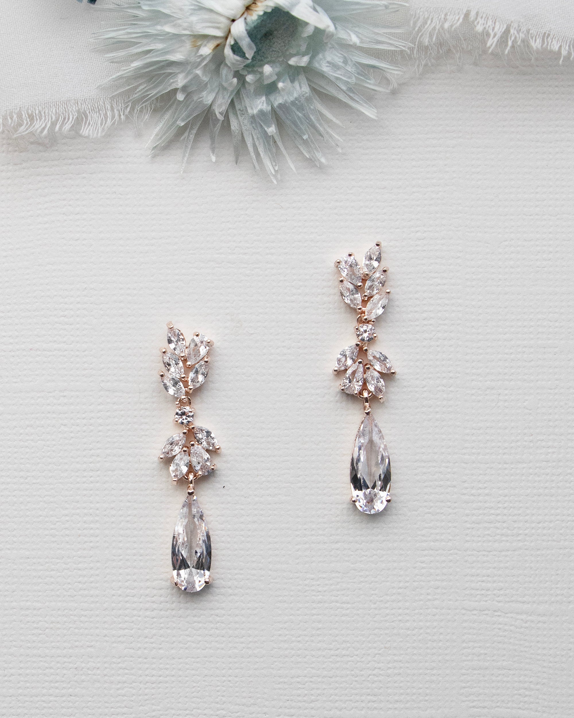 a pair of earrings sitting on top of a white surface