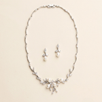 a delicate necklace and earrings set against a light beige background.