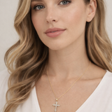 A close-up portrait of a woman with long, wavy blonde hair and a thoughtful expression, wearing a white blouse and a necklace with a cross pendant.