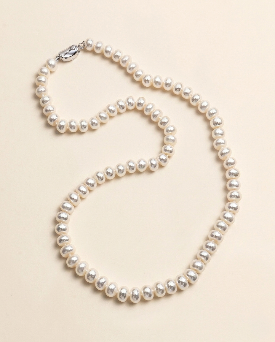 A necklace made of white pearls is displayed against a light beige background.