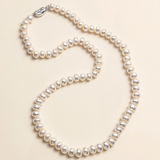 A necklace made of white pearls is displayed against a light beige background.