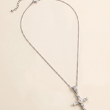 A silver cross necklace with a pendant of pearls and diamonds.