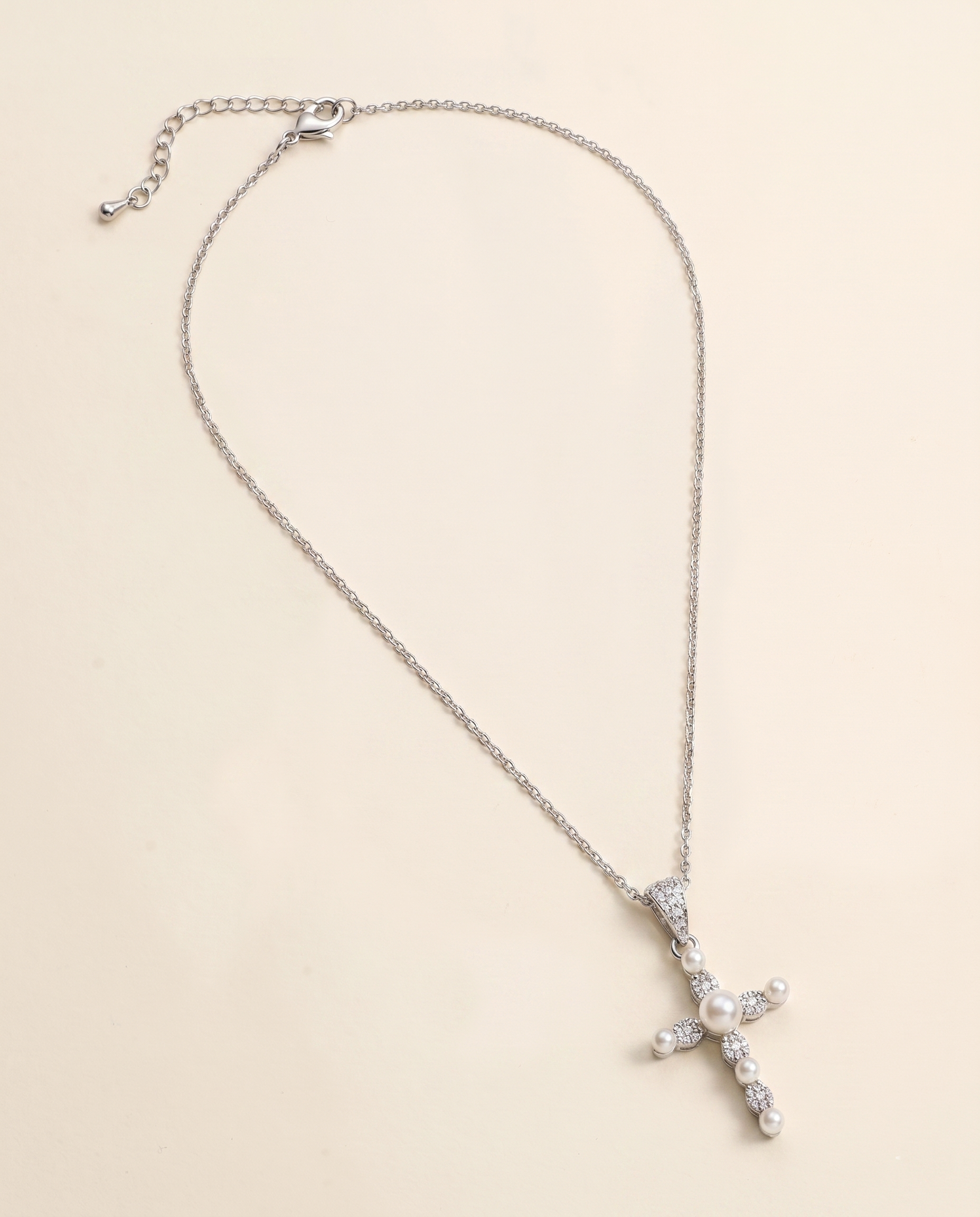A silver cross necklace with a pendant of pearls and diamonds.