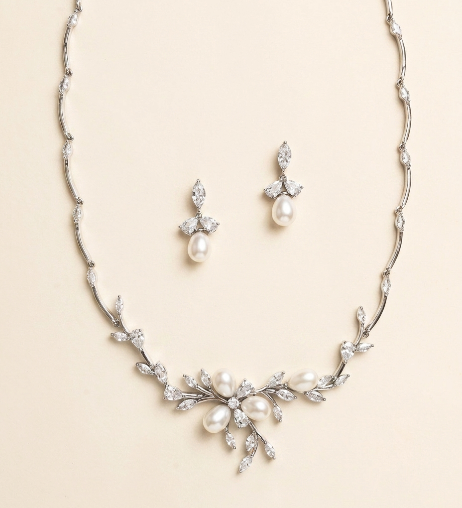 A necklace and earrings set made of silver and white diamonds, featuring a floral design with pearls and diamonds.