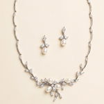 A necklace and earrings set made of silver and white diamonds, featuring a floral design with pearls and diamonds.