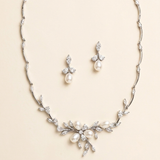 A necklace and earrings set made of silver and white diamonds, featuring a floral design with pearls and diamonds.