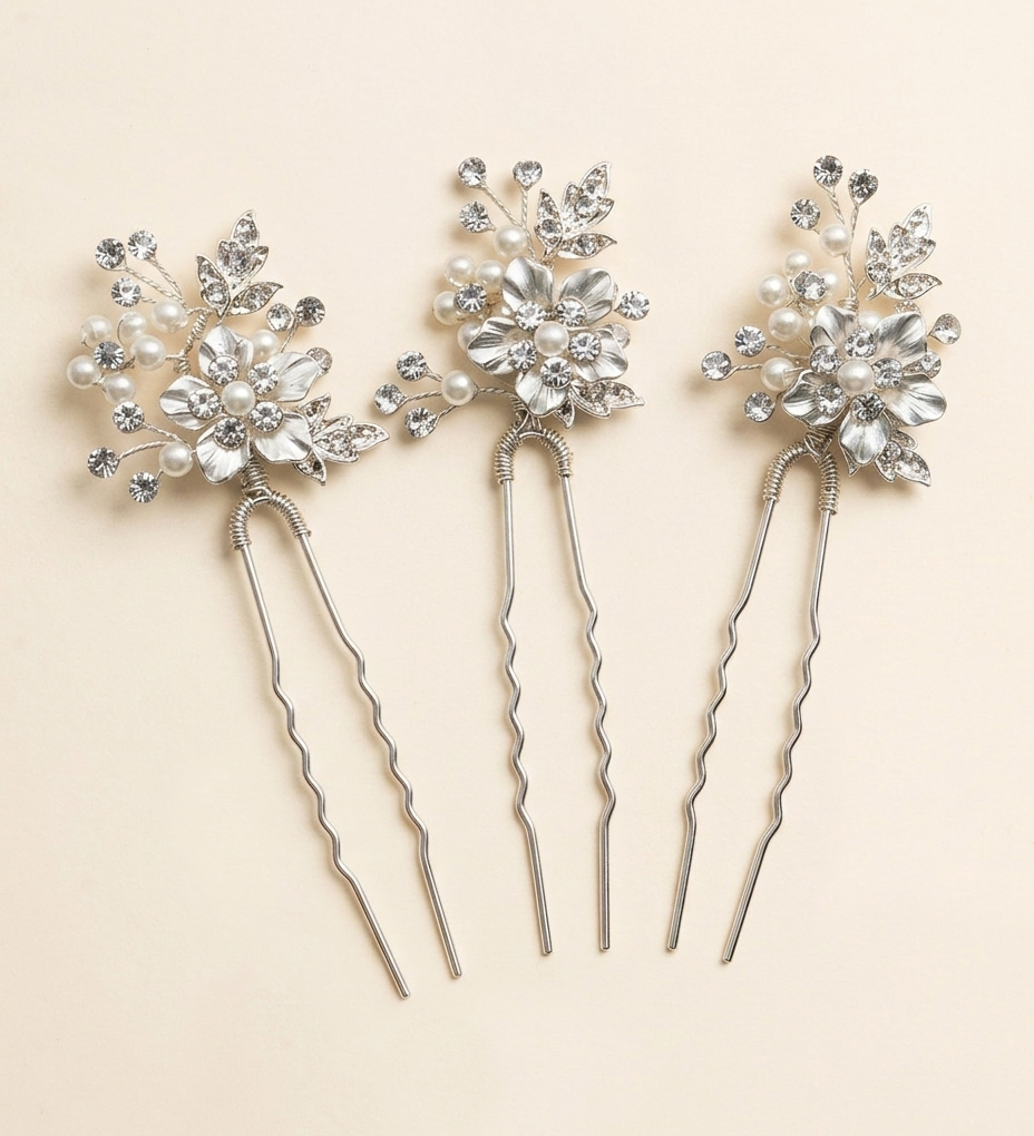 Three silver hair clips adorned with white flowers and crystals are arranged in a row against a light background.