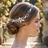 A woman with her hair styled in a bun, wearing a decorative headpiece with flowers and leaves.