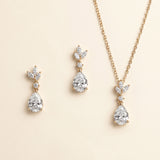 A necklace and earrings set with a gold chain and pendant adorned with small diamonds.