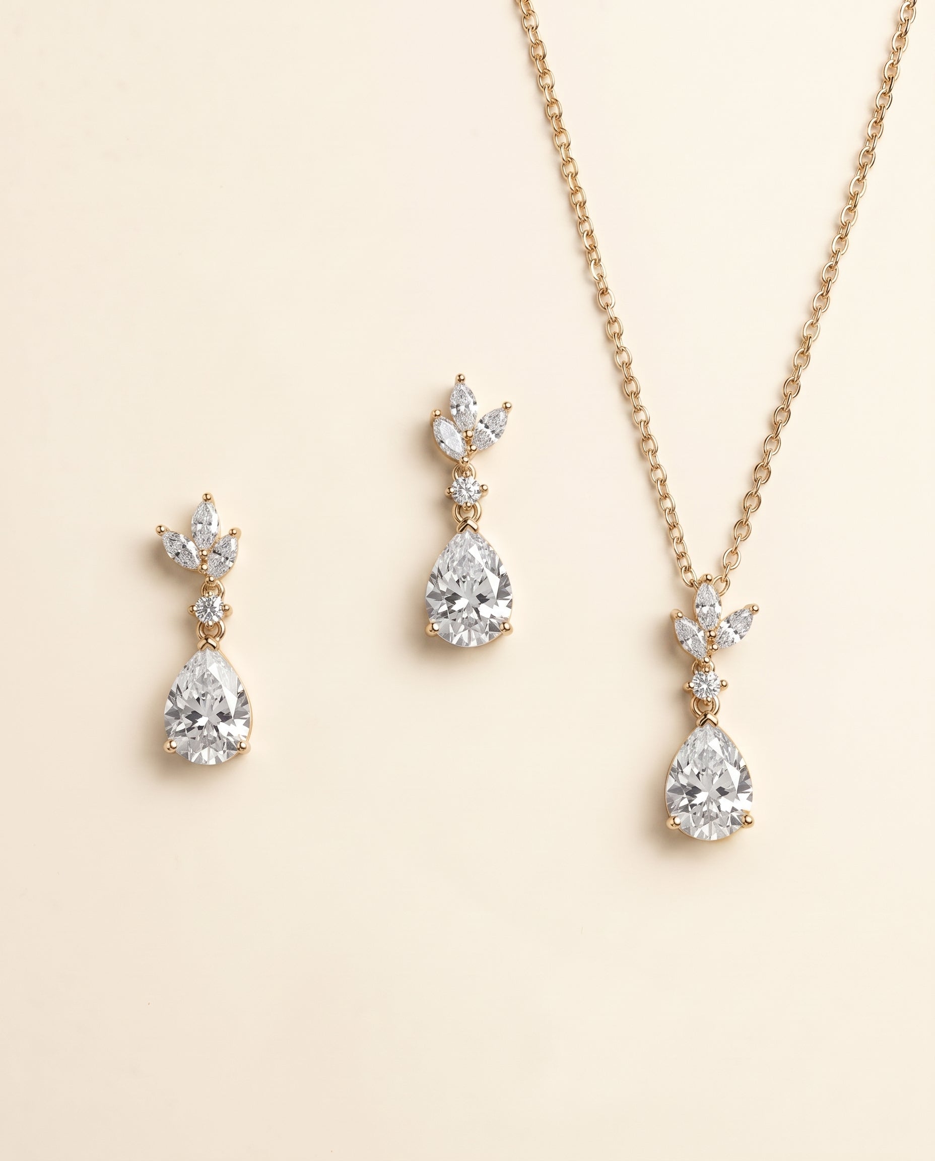 A necklace and earrings set with a gold chain and pendant adorned with small diamonds.