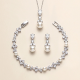 A necklace, earrings, and bracelet set made of white pearls and diamonds, arranged on a beige background.