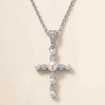 A silver cross pendant with pearls and diamonds attached to it.